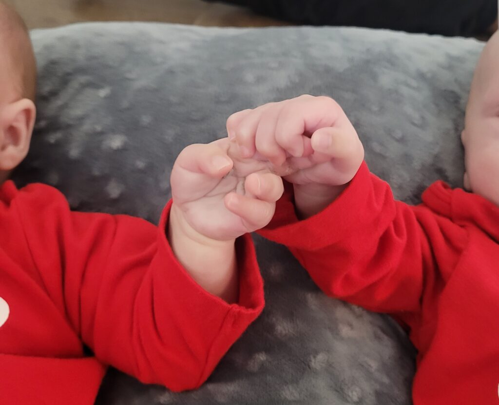 Photo of newborn twins holding hands